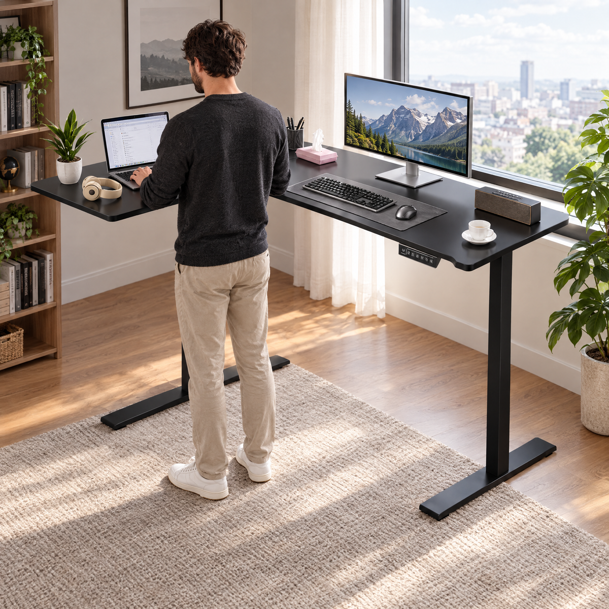 Homme travaillant debout au bureau d'angle électrique noir, vu de trois quarts dos
